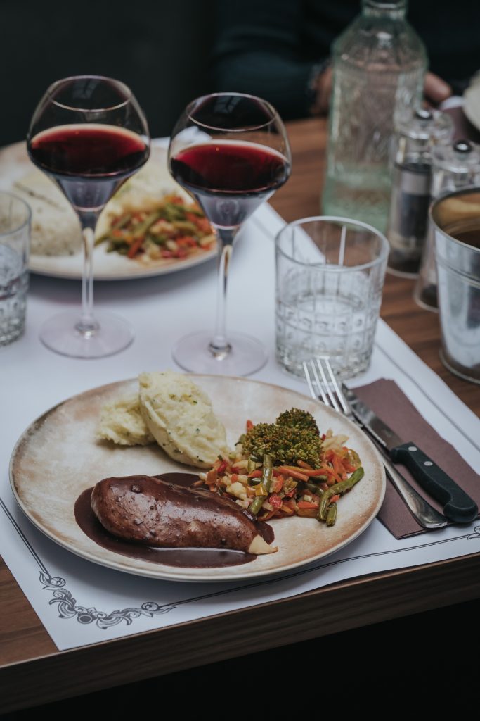 Assiette de viande et légumes accompagnée de vin rouge