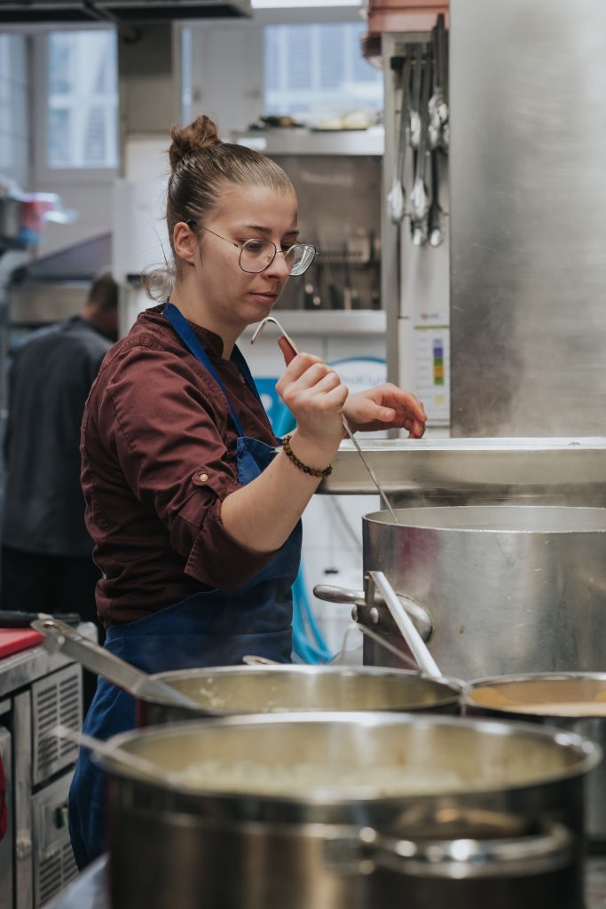 Cuisinière aux fourneaux dans la cuisine de la Brasserie Le Monge